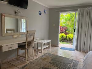 a bedroom with a desk and a mirror and a window at Santorini Guesthouse in East London +23 photos