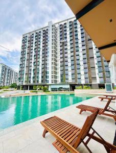 a swimming pool with chairs and a large building at Bright & Cozy High-Rise Condo in Pulong Cacawate