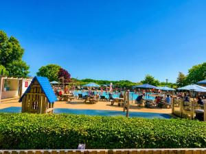 a playground with a play house and people sitting at tables at Forest Haven in Sway