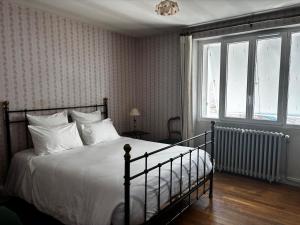 a bedroom with a bed with white sheets and a window at Maison familiale 10 pers à St Setiers in Saint-Setiers
