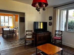 a living room with a tv and a table and chairs at Maison familiale 10 pers à St Setiers in Saint-Setiers