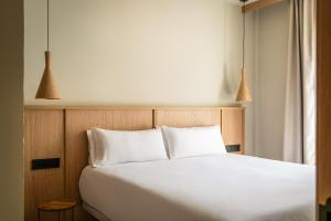 a bedroom with a white bed with two pillows at Apartamentos Estival Park in La Pineda