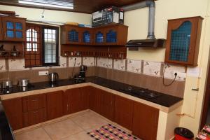 a kitchen with wooden cabinets and a stove top oven at CITADEL HOLIDAY HOME in Vythiri +39 photos