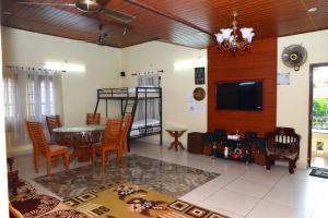 a living room with a table and chairs and a tv at CITADEL HOLIDAY HOME in Vythiri