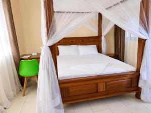 a bedroom with a canopy bed with a green chair at Mama Maendeleo Resort in Hindi