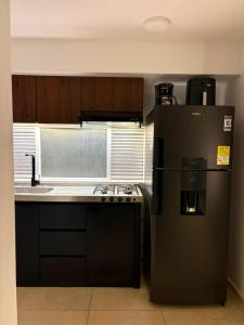 a kitchen with a black refrigerator and a sink at Monte Bravo Lodge in Yopal