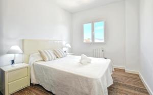 a white bedroom with a bed and a window at Son Baulo in Can Picafort