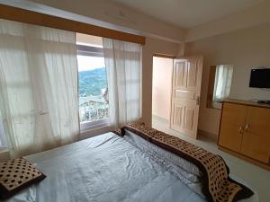 a bedroom with a large bed and a large window at CLOUDS Hotel and restaurant in Gangtok