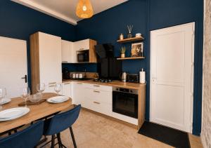 a kitchen with a wooden table and blue walls at L'Écrin de Pierre - Gare & Centre à pied - Charme & Calme in Mâcon +13 photos