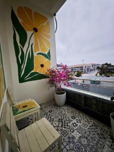 a balcony with a bench and a flower painting on the wall at The Little Leaf Hostel - Restaurant & Rooftop Bar CatBa in Cat Ba