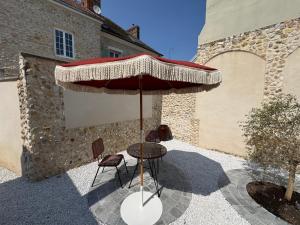 a table and chairs under an umbrella on a patio at Charmante Maison avec Jardin Privé - PACY SUR EURE in Pacy-sur-Eure