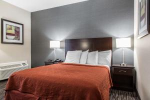 a hotel room with a bed with a red bedspread and two lamps at Danbury Inn & Suites in Danbury