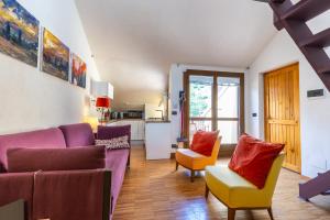 a living room with purple and yellow furniture and a kitchen at Hostdomus - Purple Apartment in Cesana Torinese