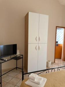 a bedroom with a white cabinet and a television at Nalusa Home in Sarno