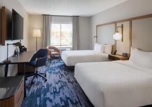 a hotel room with two beds and a desk at Fairfield By Marriott Middletown Monroe in Middletown