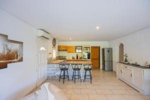 a kitchen with three bar stools in front of a counter at Appartement Aléria avec jardin in Aléria