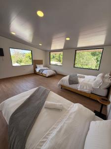 ein Schlafzimmer mit zwei Betten und drei Fenstern in der Unterkunft Salento River Hotel in Salento