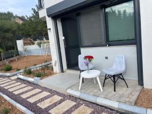 two chairs and a table and a vase of flowers on a porch at Oksijen in Urla
