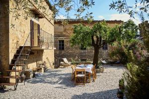 a patio with a table and chairs in front of a building at CasaBianchini Charming Home Val d'Orcia in Monticchiello