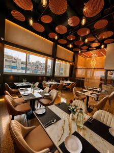 a restaurant with tables and chairs and windows at Hotel Vedic Roots in Varanasi