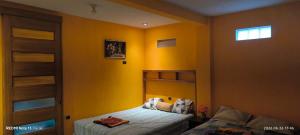 a bedroom with yellow walls and a bed and a window at La Casa Amarilla in Sololá