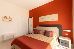 a bedroom with a bed with an orange wall at Resid Enza Palazzo Sciacca in Patti +4 photos