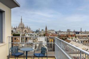 a balcony with chairs and a table and a view of the city at B&B HOTEL Milano Duomo Velasca in Milan