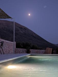 a swimming pool at night with the moon in the sky at Thelea Mani in Kafióna