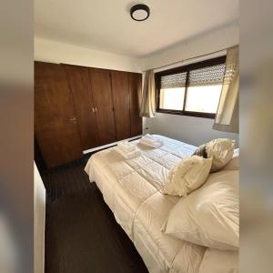 a bedroom with a bed with white sheets and a window at Magnolia Tempo in Esquel