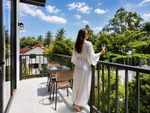 a woman standing on a balcony holding a glass of wine at Beachside Villa in Ko Phangan