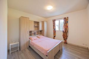 a bedroom with a bed with pink sheets and a window at Appartement Aléria avec jardin in Aléria
