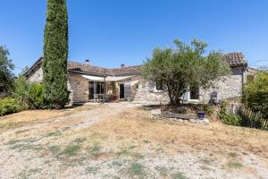 an old stone house with a tree in the yard at Maison de Charme en Pleine Nature in Bournazel