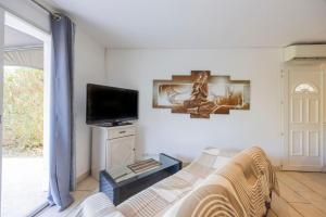 a living room with a couch and a tv at Appartement Aléria avec jardin in Aléria
