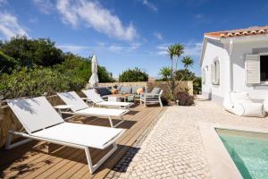 a patio with white chairs and a swimming pool at Seashore Escape by Lisbeyond in Aljezur