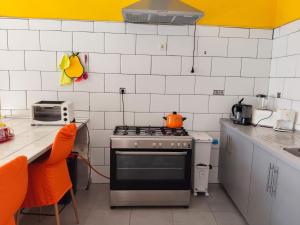 a kitchen with a stove and a counter with orange chairs at Lindas Vistas in Tías