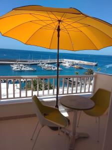 a yellow umbrella on a balcony with a table and chairs at Rent Vacancy Arcoiris in Tías