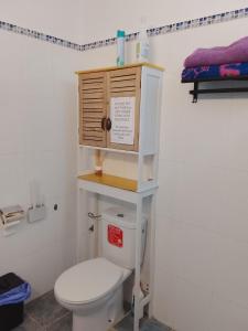 a bathroom with a toilet with a wooden cabinet above it at Rent Vacancy Arcoiris in Tías +11 photos