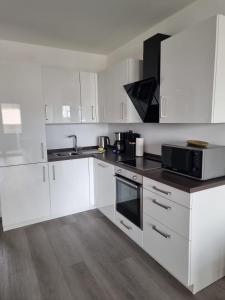 a kitchen with white cabinets and a black microwave at Apartment Affengrün in Weyhausen