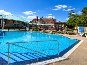 a large blue swimming pool in front of a house at Forest & Beach Escape in Sway