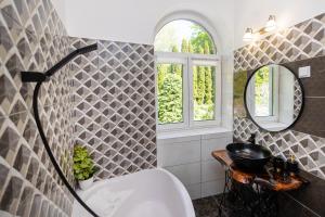 a bathroom with a tub and a sink and a mirror at Jákób-Vár Vendégház in Füzér +57 photos