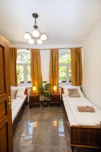 a bedroom with two beds and two windows at Jákób-Vár Vendégház in Füzér