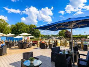 a patio with tables and chairs and a blue umbrella at Forest lodge in Sway