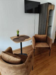 a living room with two chairs and a table and a tv at Apartament ANTONIA in Olesno
