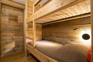 a bunk bed in a room with wooden walls at Les Brigues - Appartement avec vue sur la montagne et accès aux pistes in Courchevel
