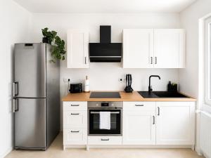 a kitchen with white cabinets and a stainless steel refrigerator at Boutique Hotel Celler Altstadt - 24h Check-in in Celle