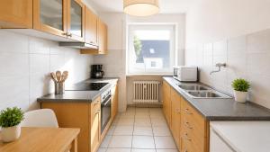 a kitchen with wooden cabinets and a sink and a window at Pulheim Living 5 in Pulheim