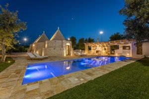 a swimming pool in front of a house at night at Villa Trulli del Gelso in Carovigno