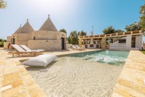 a swimming pool in front of a house at Villa Trulli del Gelso in Carovigno