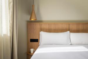 a bedroom with a white bed with a wooden headboard at Apartamentos Estival Park in La Pineda