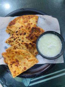 a black plate of food with a bowl of dip at Hotel Raj Bed And Breakfast in Agra